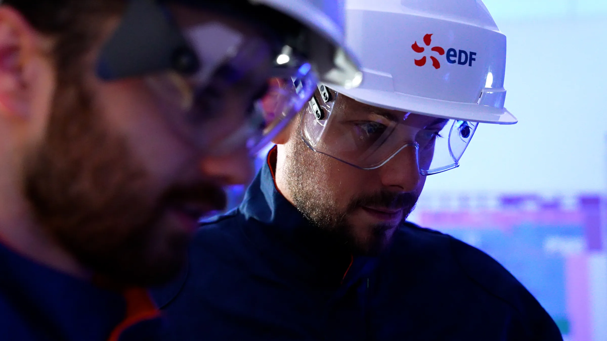 Deux intervenants en casque et lunettes de protection, concentrés sur un écran lors d’un briefing